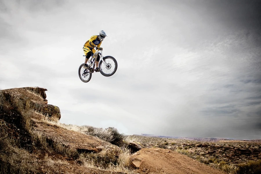 Ein Mountainbiker springt von einem Felsen