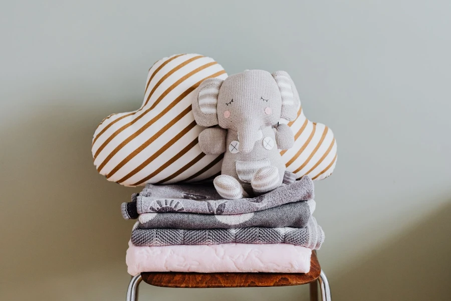 A stack of blankets with a stuffed elephant doll