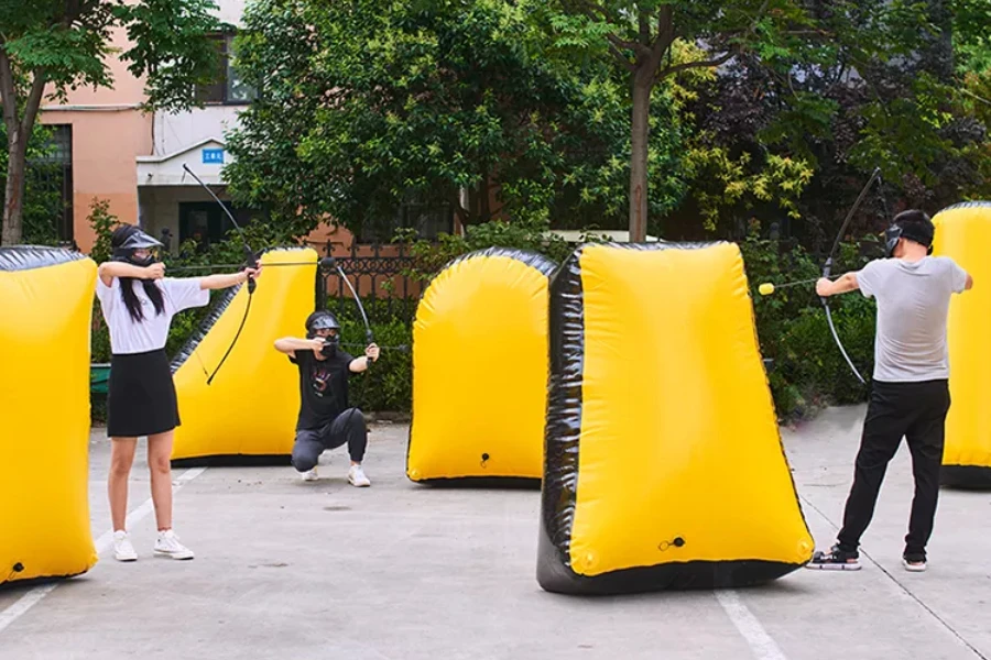 Inflatable yellow bunkers and people playing archery tag