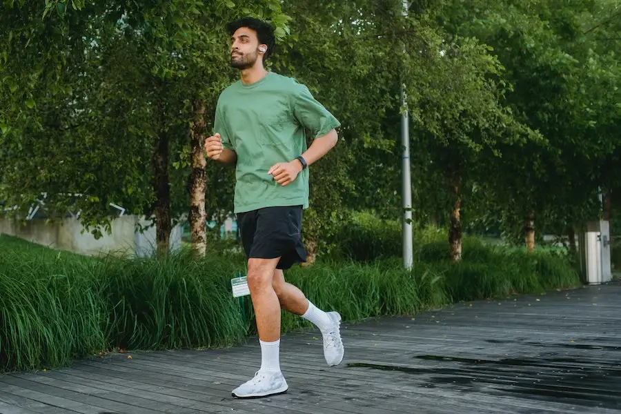 Hombre trotando en una camiseta verde con pantalones cortos negros