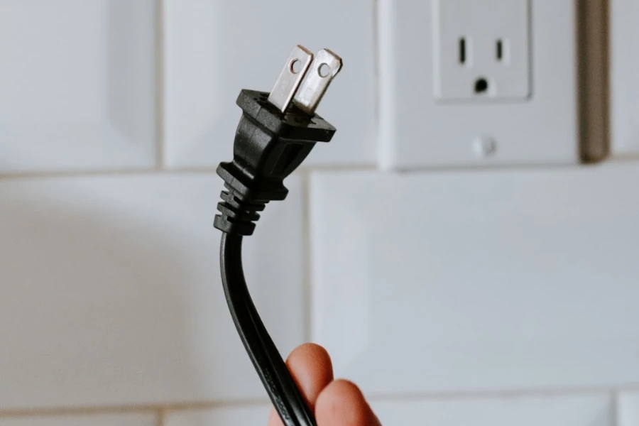 Person holding a plug that’s unplugged in front of a wall outlet