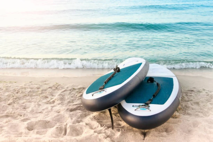 Two paddle boards on sand by the beach