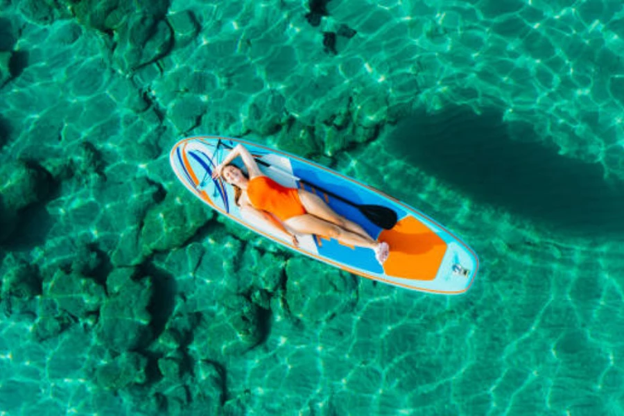 Frau liegt auf einem Paddelbrett im klaren Wasser