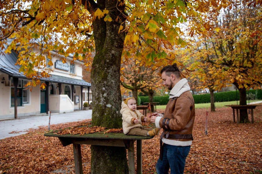 Homme dans un manteau de couleur intégrale jouant avec un bébé