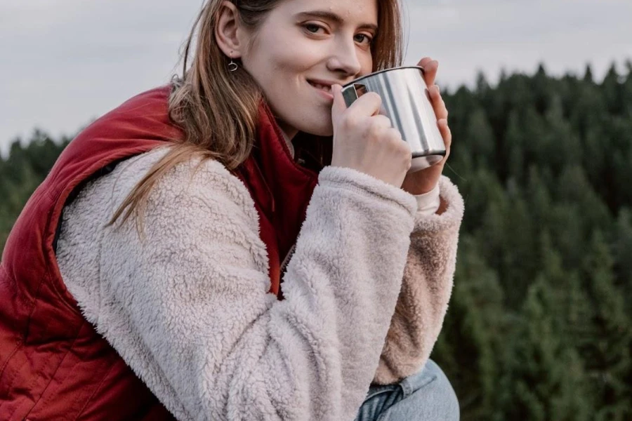 Mujer sosteniendo una taza mientras usa un chaleco rojo