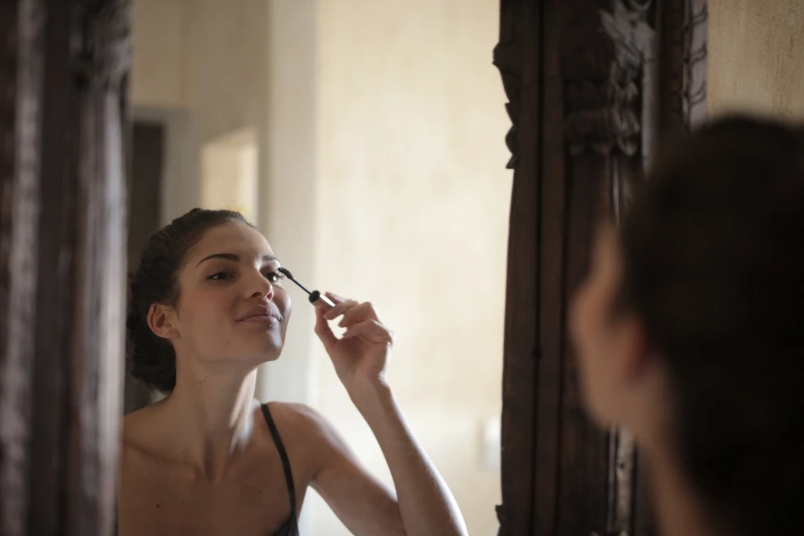 Woman holding mascara brush close to her eye