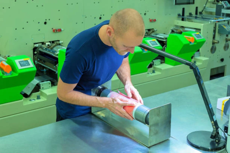 Worker preparing a photopolymer relief plate on a printing cylinder