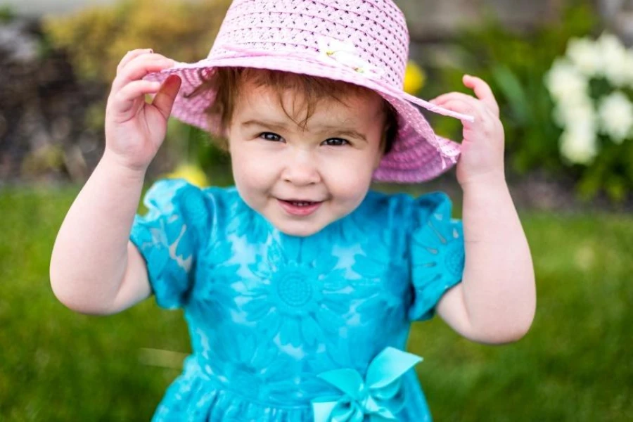 Petite fille au chapeau de soleil en paille rose