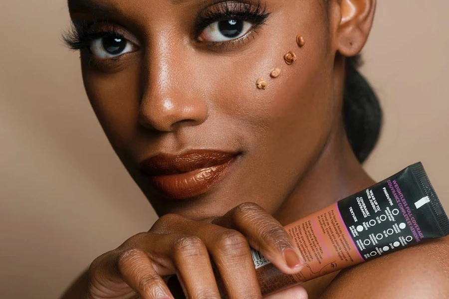 Mujer negra mostrando un producto de belleza de varios tonos