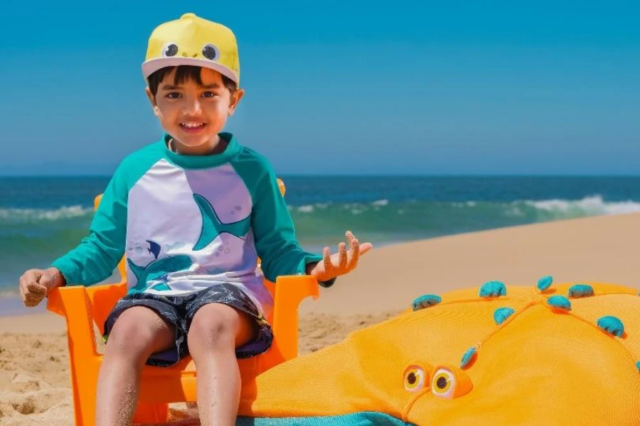 Ragazzo in spiaggia che indossa un cappello a tesa piatta giallo