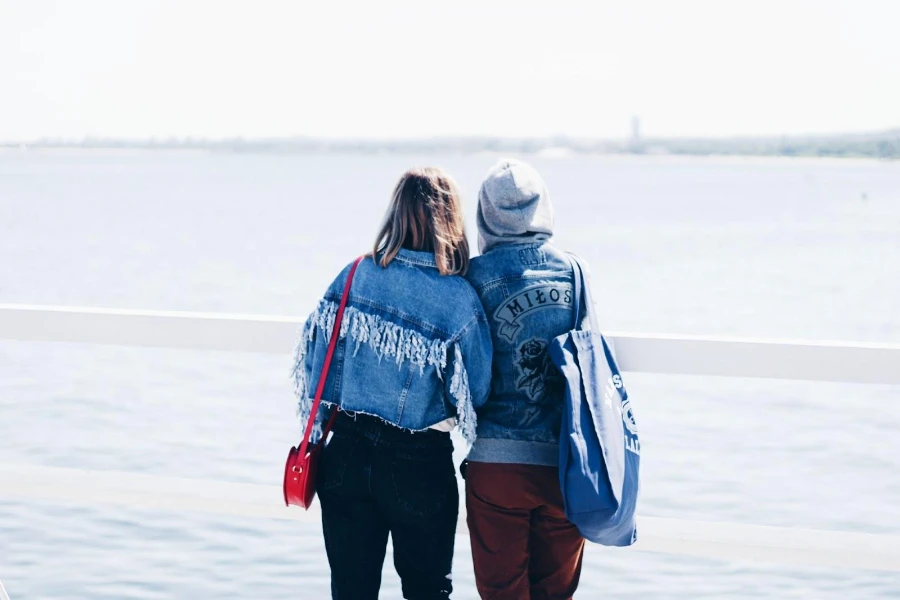 Menschen in Jeansjacken starren auf das Meer