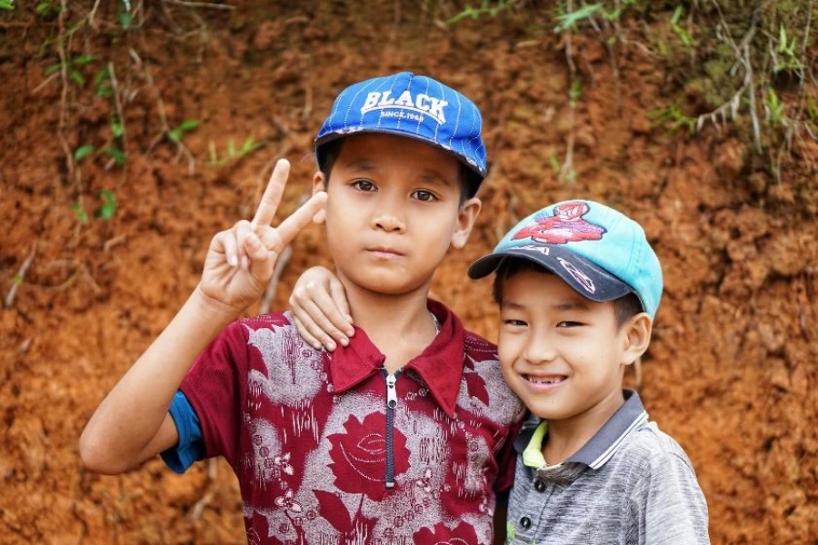 Dua anak laki-laki mengenakan topi biru dengan logo bordir khusus