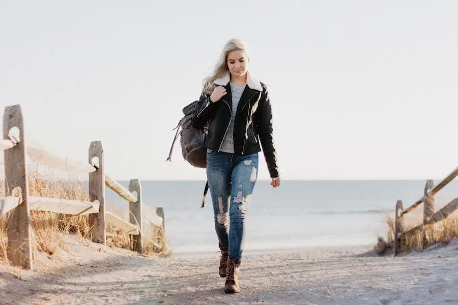 Woman walking while wearing jacket and denim