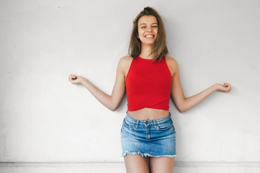 ragazza allegra con minigonna in denim e top rosso