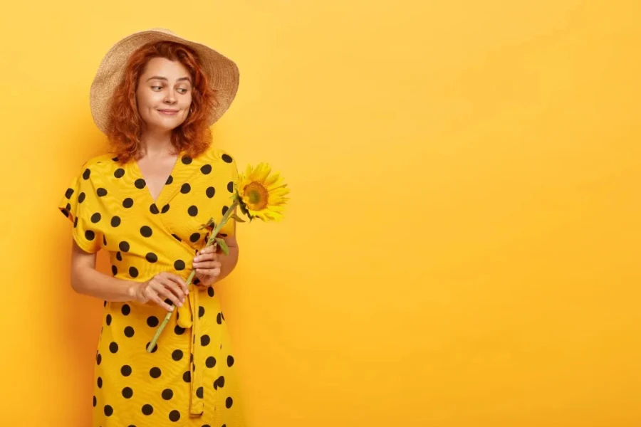 Dame in einem gelben Kleid, die eine Sonnenblume hält