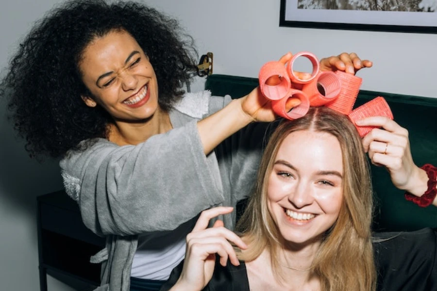 Wanita bersenang-senang meletakkan rol rambut di rambut mereka