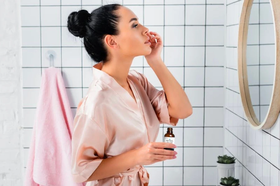 Une femme regardant dans le miroir et appliquant du sérum pour la peau