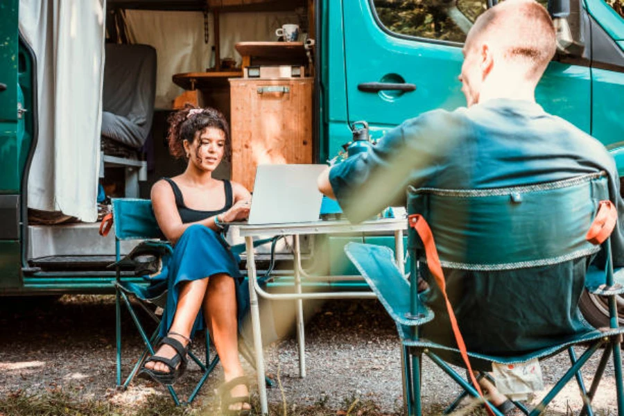 Paar sitzt vor Wohnmobil mit Klapptisch und Stühlen