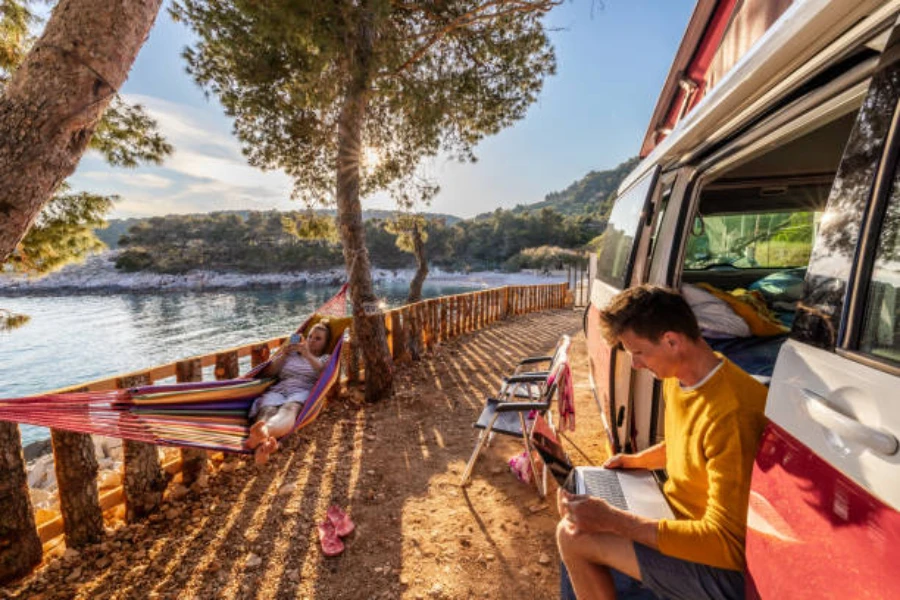 Karavan ve gölün yanındaki hamakta dinlenen kadın