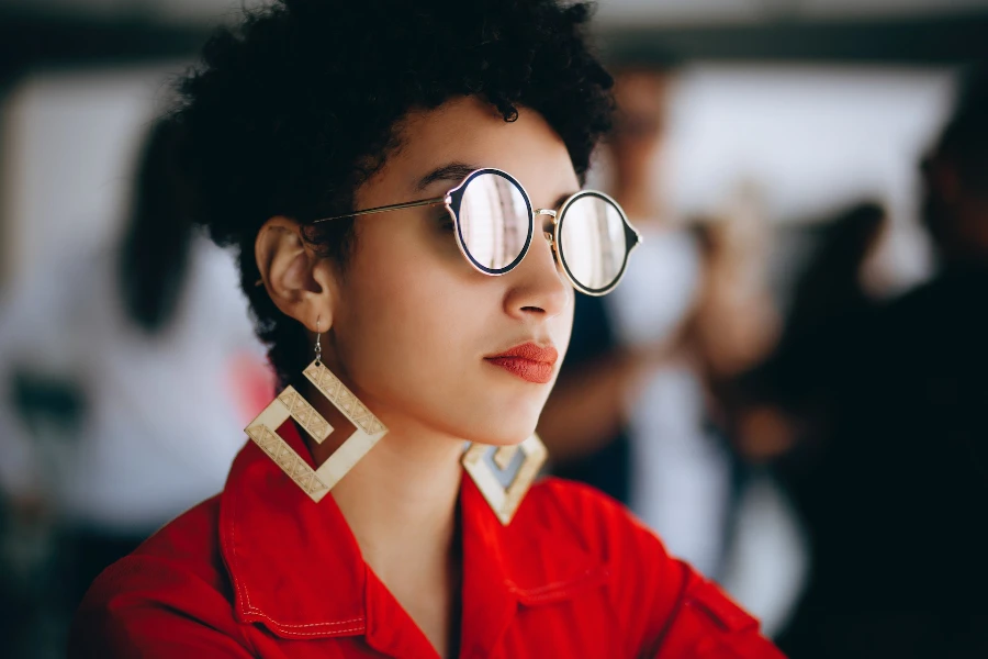 Frau trägt ein rotes Hemd, eine Sonnenbrille und große Statement-Ohrringe