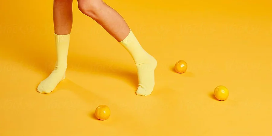 Legs with yellow tube socks on orange backdrop