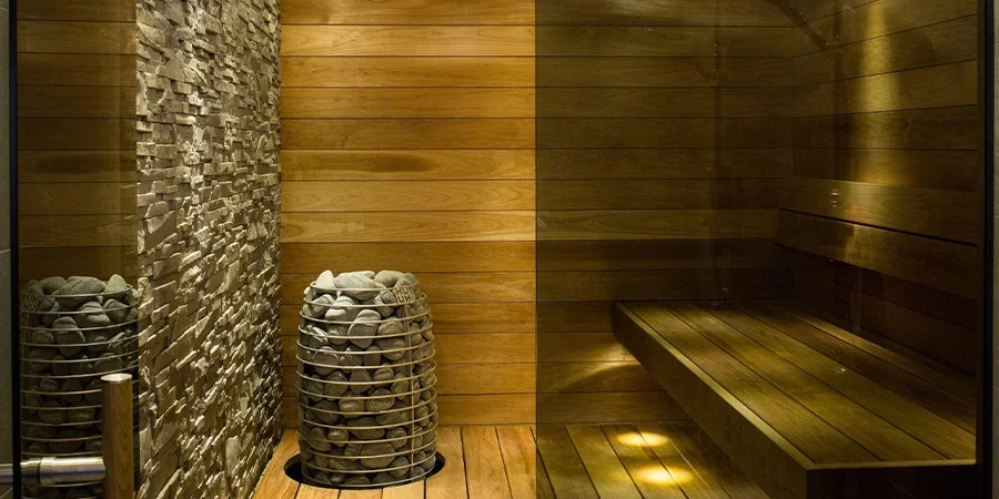 Nordic home wooden sauna with heat stones and stone accent wall
