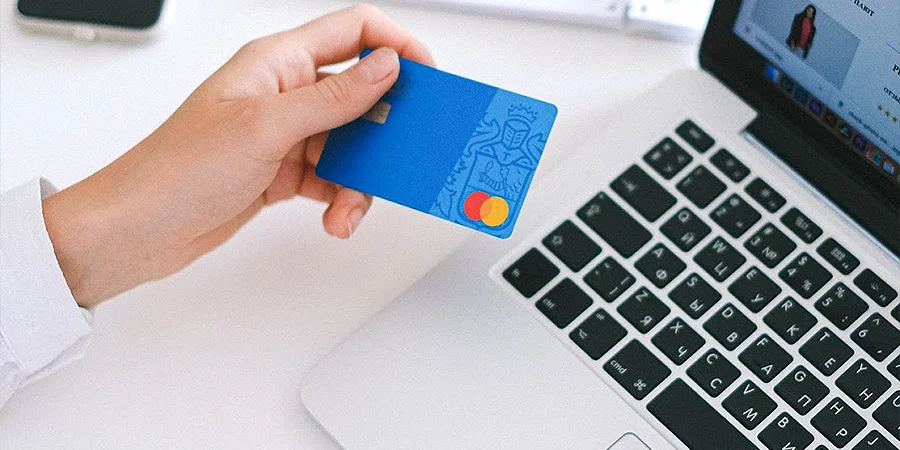 Person holding bank card in front of a laptop