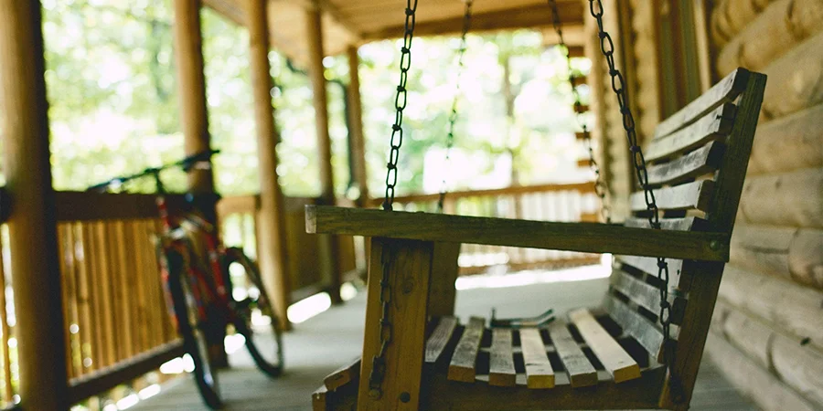 a wooden hanging patio swing at a log cabin