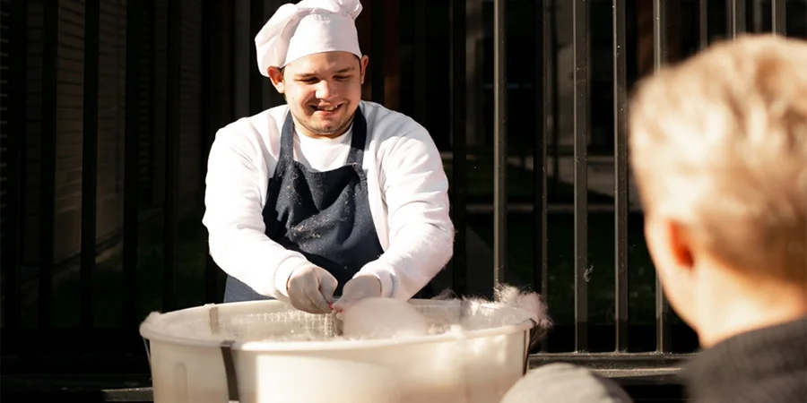 A chef delightfully smiling at a cotton candy customer