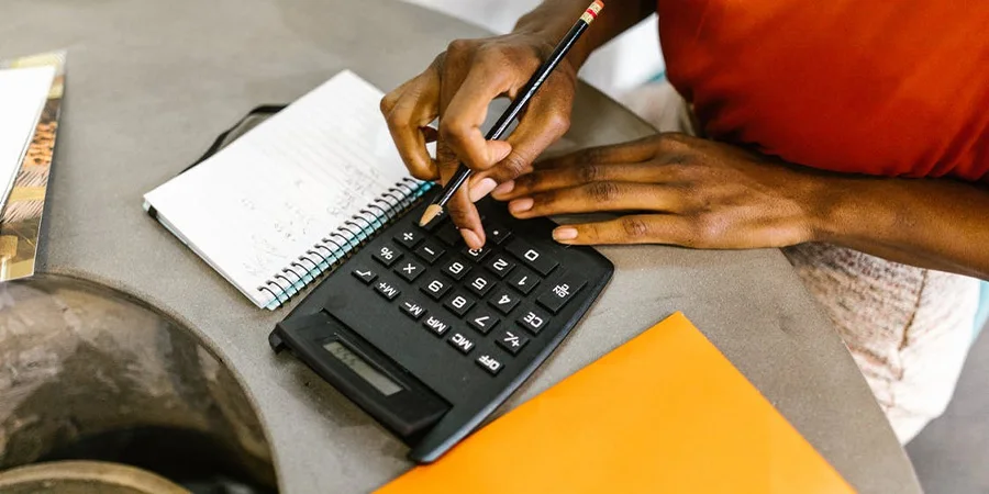 person preparing a budget with a calculator and notebook