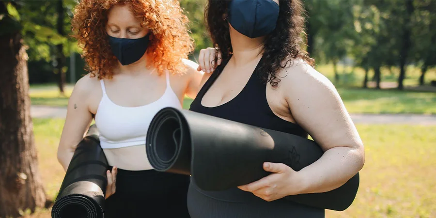 Two women with yoga mats dressed in activewear