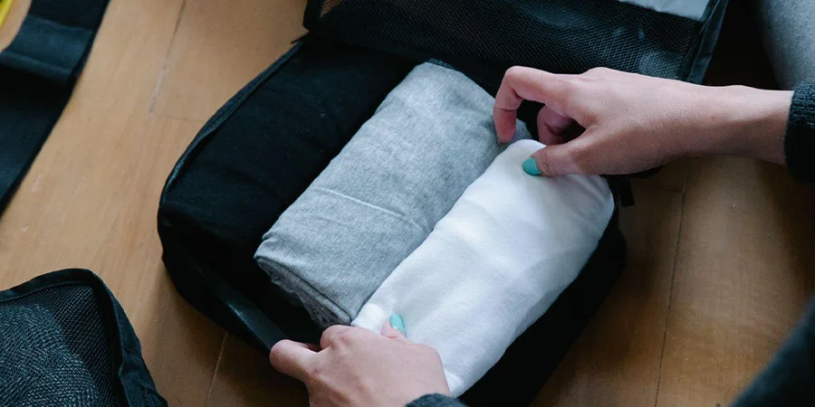 Person putting folded clothes in pouch