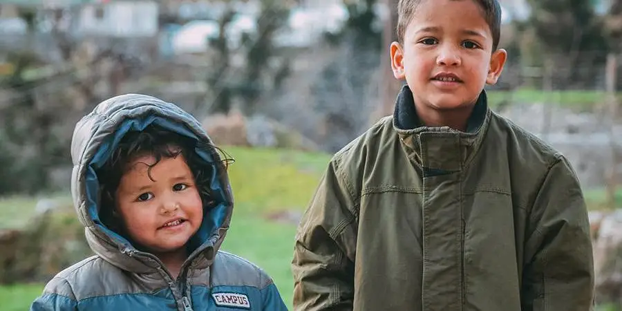 Two boys wearing jackets and denim pants