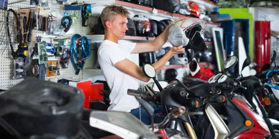 Caucasian male shop owner holding a helmet in a motorcycle shop.