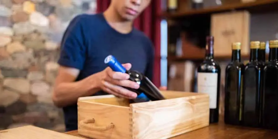 Person packing a wine bottle in a wooden gift box