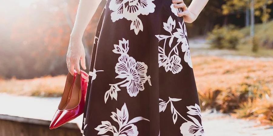 Woman in floral skirt holding red shoes