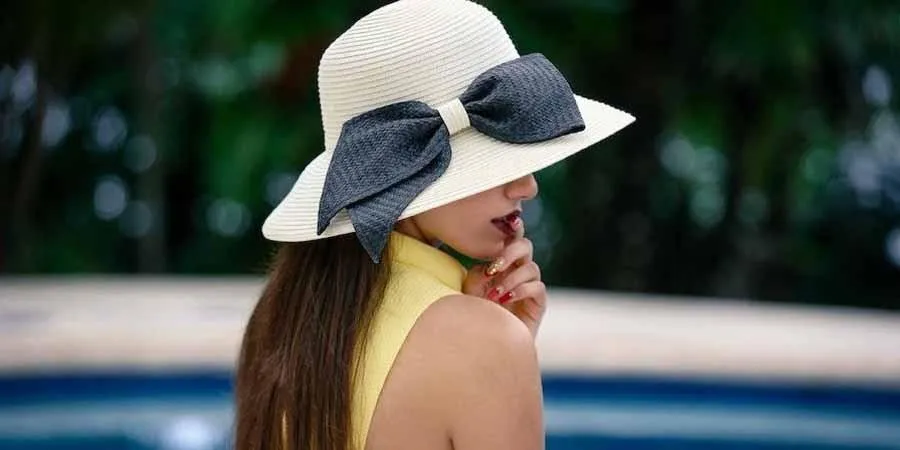 Woman styling a bow hat with a yellow top