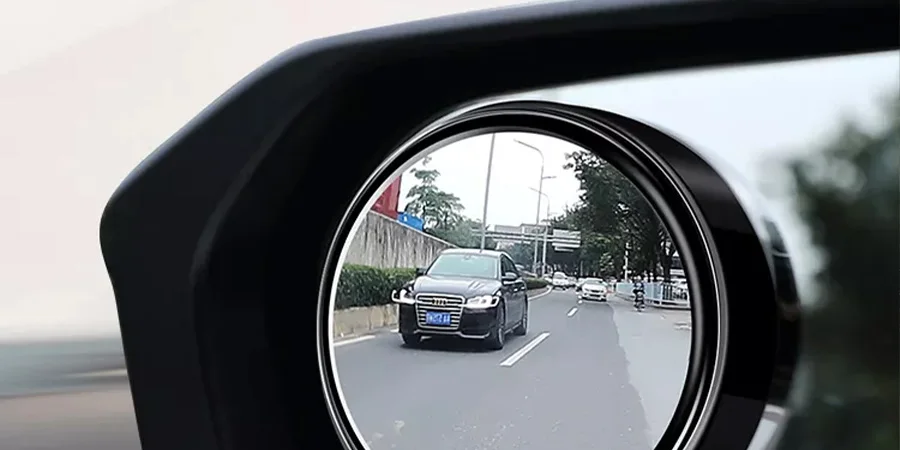 A side mirror showing a black car in the rearview