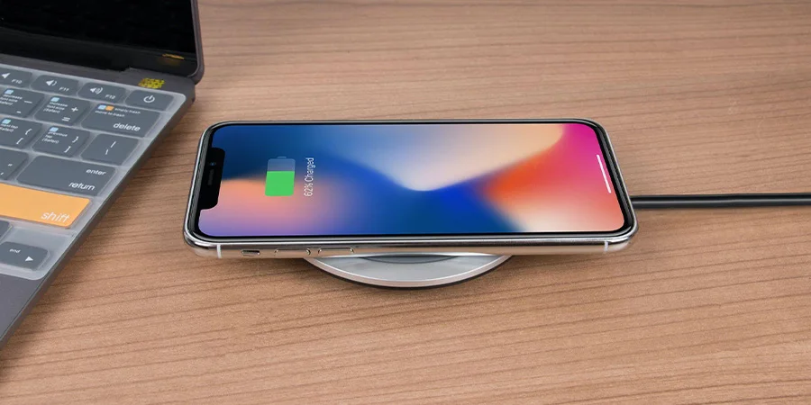 iPhone charging on a wireless charging pad on a desk