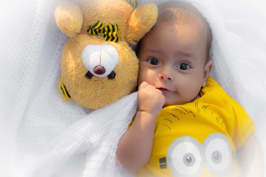 Seorang bayi dengan boneka di sampingnya