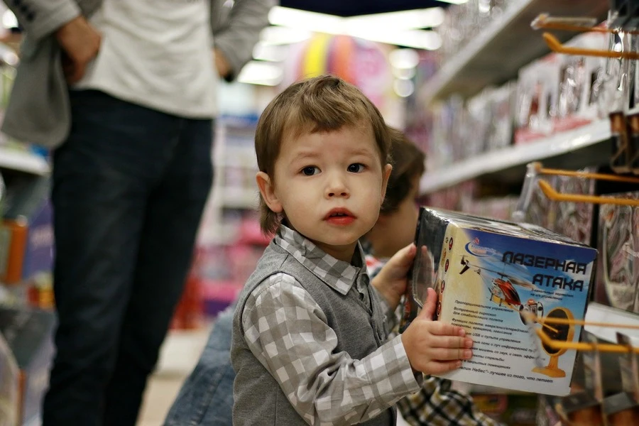 Um menino de pé com uma caixa de brinquedos