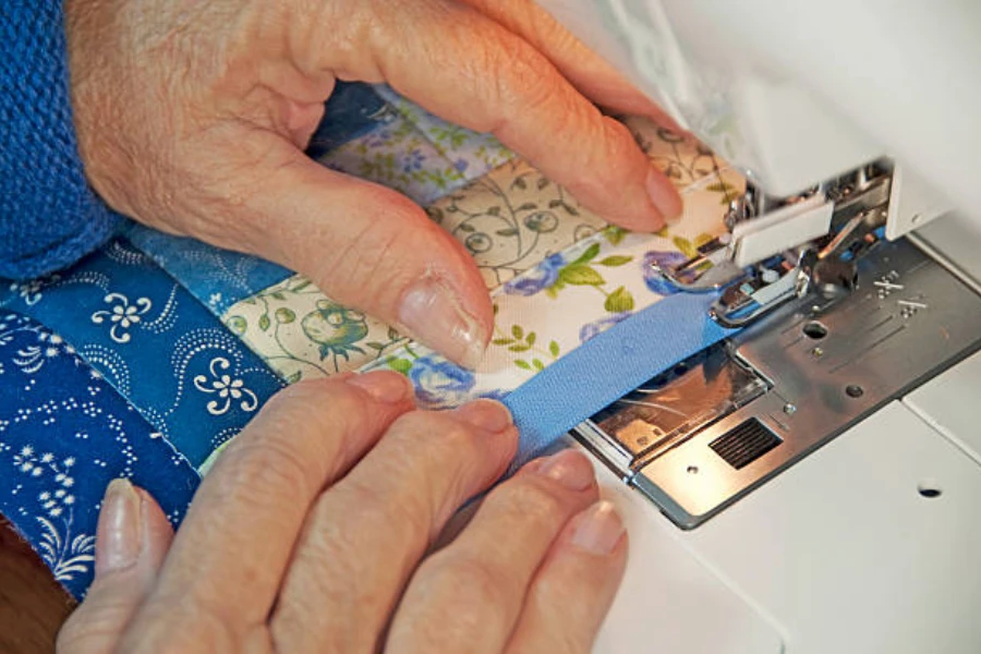 A close-up of hands sewing a quilt on a machine