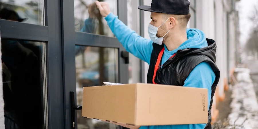 A delivery man delivers a parcel up to the doorstep