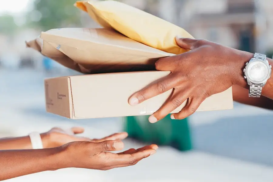 Uma pessoa recebendo uma caixa e dois pacotes de papel kraft