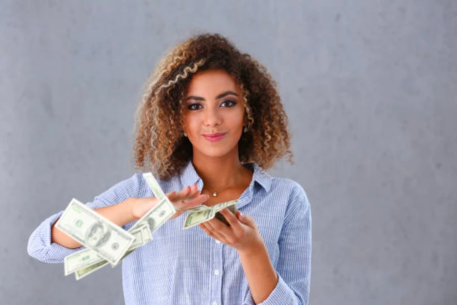 Una mujer tirando dinero de sus manos.