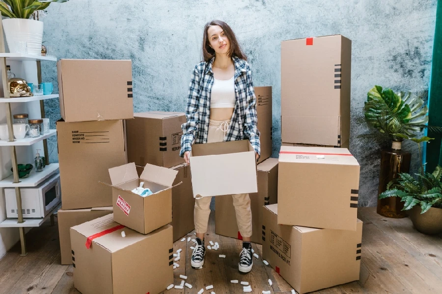 Une femme avec plusieurs boîtes en carton ondulé