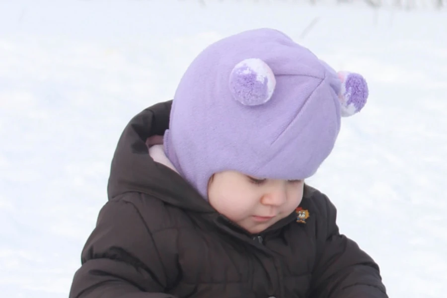 Baby in light purple balaclava hat with pompom ears