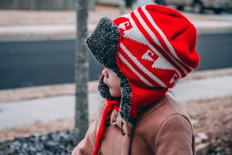 Baby in patterned ear flap toque with gray fur