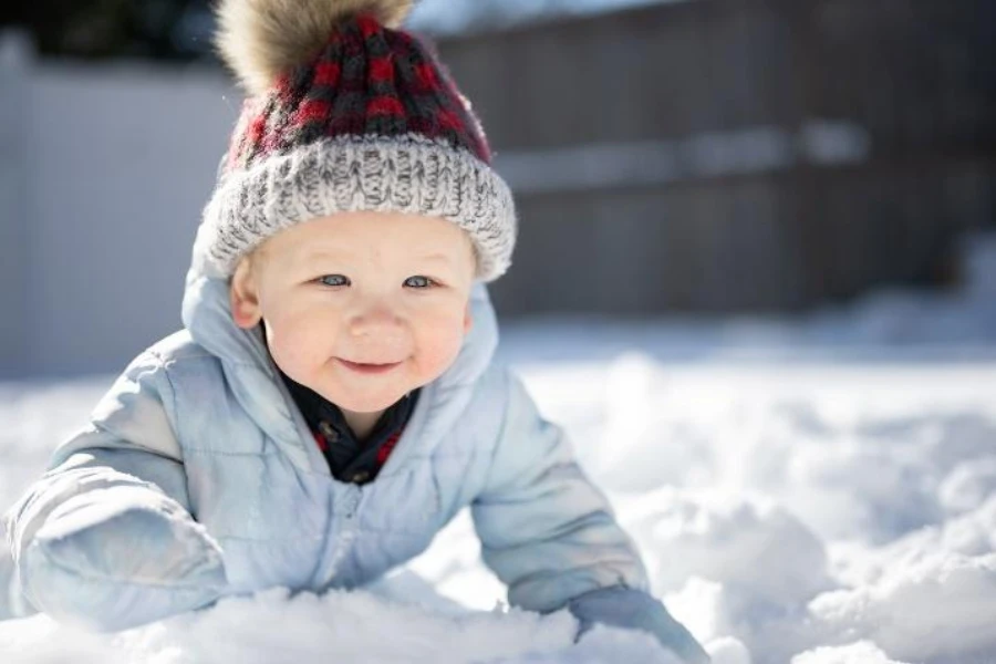 Baby trägt eine Strickmütze mit Fellbommel