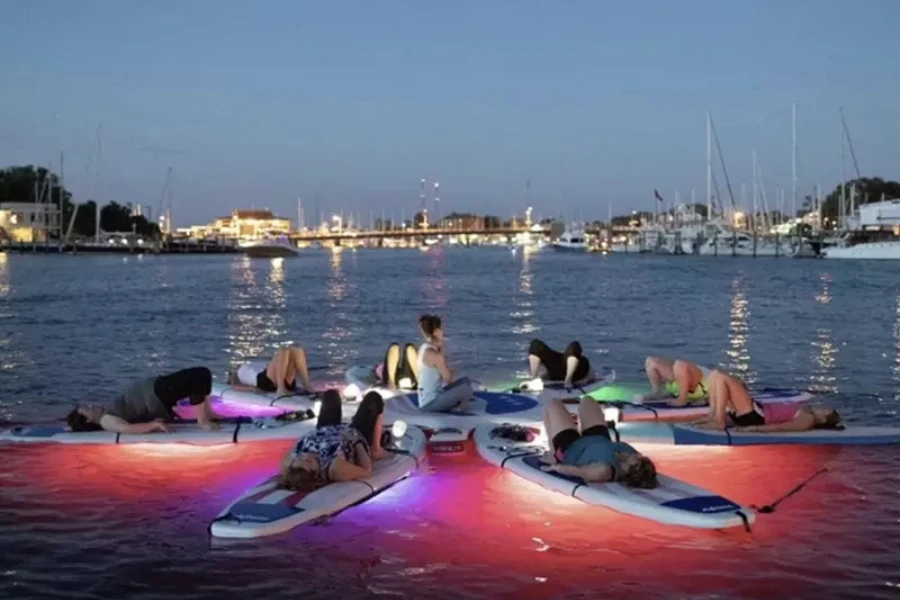 Circle of paddle boards on water with underwater lights